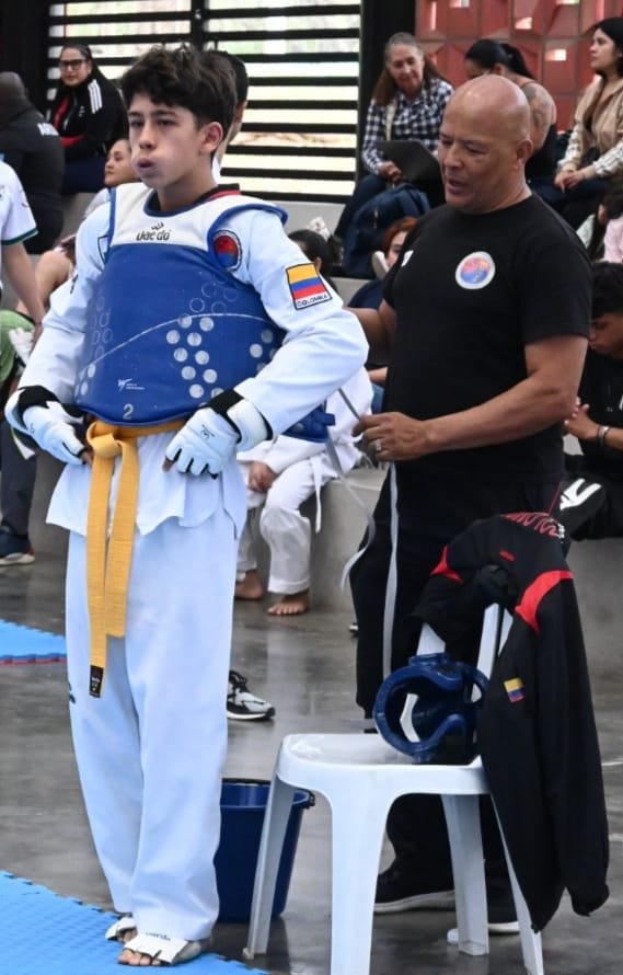 Entrenador del Club Master Quint ajustando protector a niño antes de combate de taekwondo — Medellín Colombia