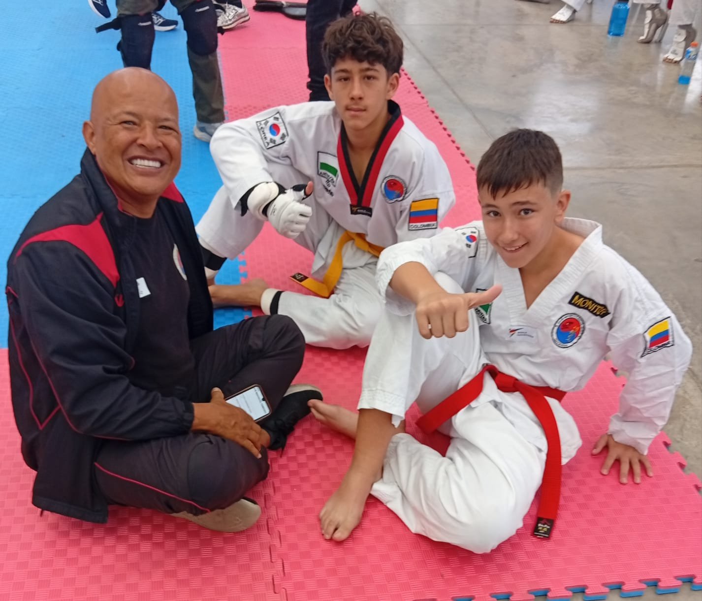 Gran Maestro Renson Quintero Castro con atletas de Colombia sentados en tatami durante competencia de taekwondo — Club Master Quint